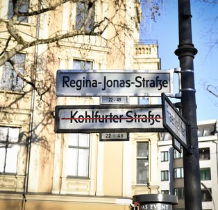 Wechsel der Straßenbeschilderung zur Einweihung der neuen Regina-Jonas-Straße, 2025.<br><i>FHXB Friedrichshain-Kreuzberg Museum, Foto: Marcelina Wellmer</i>
Straßenbeschilderung Regina-Jonas-Straße